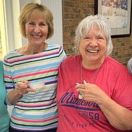 Two older women smiling and holding bowls